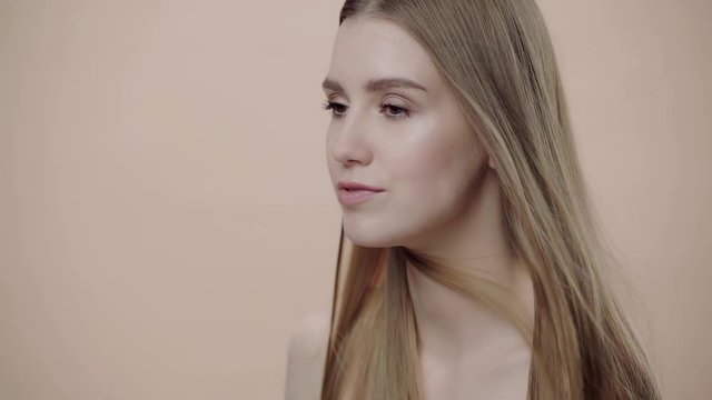 slow-motion of girl touching hair isolated on beige 