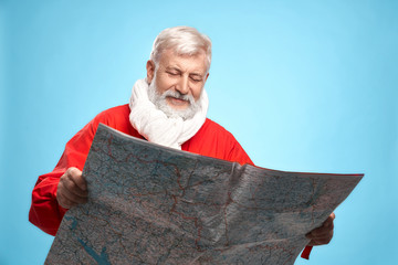 Mature Santa Claus with paper map planning christmas day