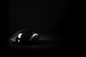 black computer mouse on a black background with a place for inscription