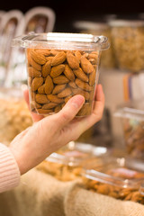 Female hand choosing almonds in the store. Concept of healthy food, bio, vegetarian, diet.