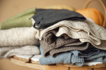 Woolen sweaters of pastel shade lie in set on wooden table, yellow background. Concept recycling clothes