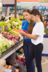 Teen girls shopping in the supermarket at the vegetable section. Choosing daily product