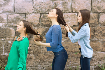 Teen girls and mother have fun at old brick wall background