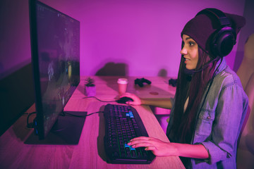Side profile photo view of young millennial gamer expressing astonishment violet purple on face pressing keyboard in pink lights at night © deagreez