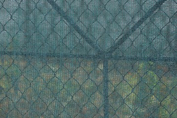 green texture of metal mesh and a piece of cloth in the fence wall