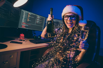 Photo of drunk it specialist professional lady sparkling wine glass and bottle attend corporate newyear x-mas party say toasts wear many garland lights santa cap glasses indoors