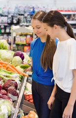Teen girls shopping in supermarket reading product information. Choosing daily product