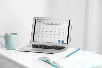 Modern laptop with calendar on screen in office