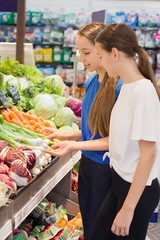 Teen girls shopping in supermarket reading product information. Choosing daily product