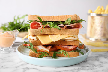 Tasty sandwich with chicken, ham and bacon served on white marble table