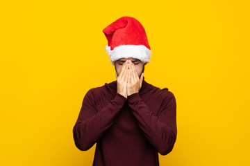 Fototapeta na wymiar Man with christmas hat over isolated yellow background with tired and sick expression