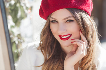 Portrait of attractive young girl outdoors. Beautiful urban lady smiling at camera. Female with red lips.