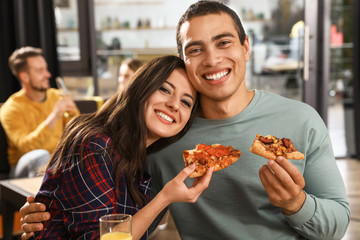 Young couple eating delicious pizza in cafe