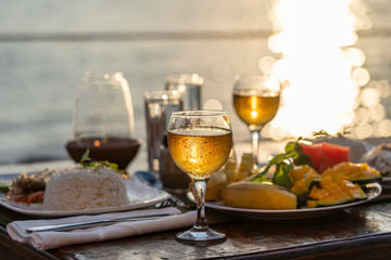 Two wine glasses on wooden table near sea on the tropical beach during sunset