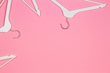 White wooden clothes hangers on pastel pink background. Shopping, sale, promo, new season concept