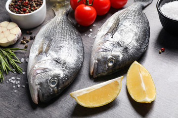 Raw dorada fish on grey table, closeup