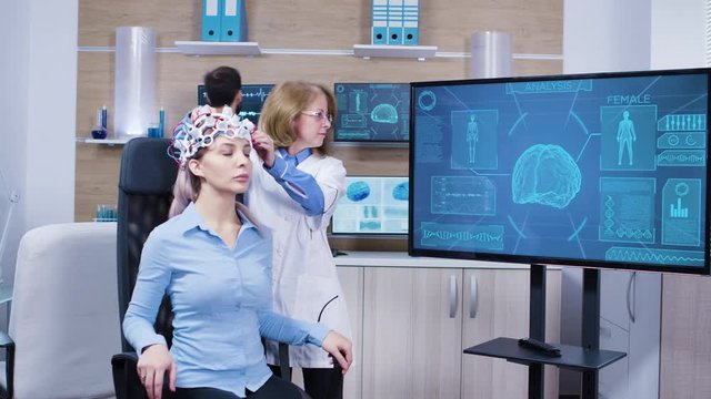 Neurology female doctor making adjustments to brainwaves headset