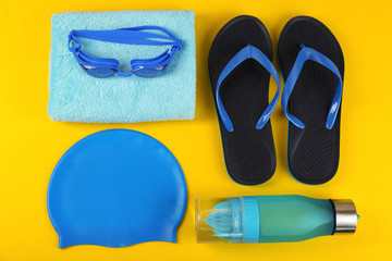 Flat lay composition with swimming accessories on yellow background