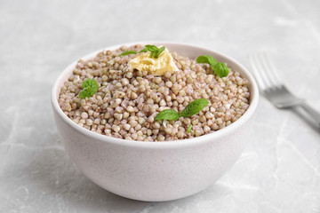 Tasty buckwheat porridge with butter on grey marble table