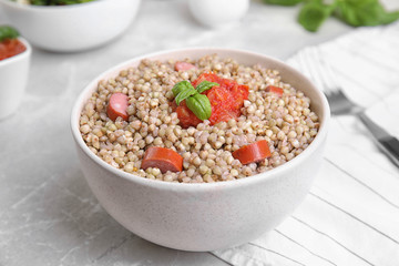 Tasty buckwheat porridge with sausages on grey marble table