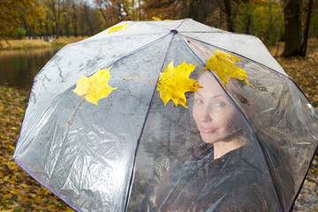 woman under a transparent umbrella on  autumn day on the lake shore..