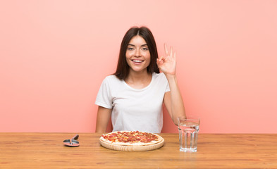 Obraz na płótnie Canvas Young woman with a pizza showing ok sign with fingers