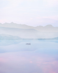 boat on a beautiful mountain lake with reflections on the water on a foggy day at sunset. misty asian landscape