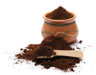 Instant espresso powdered coffee in clay pot with small wooden spoon, isolated on white background