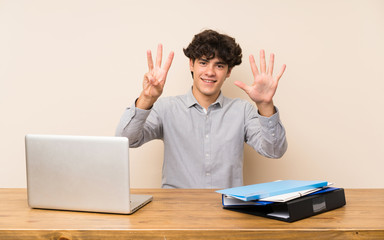 Young student man with a laptop counting eight with fingers