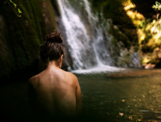 mujer de espaldas después de tomar un baño en una cascada balneario