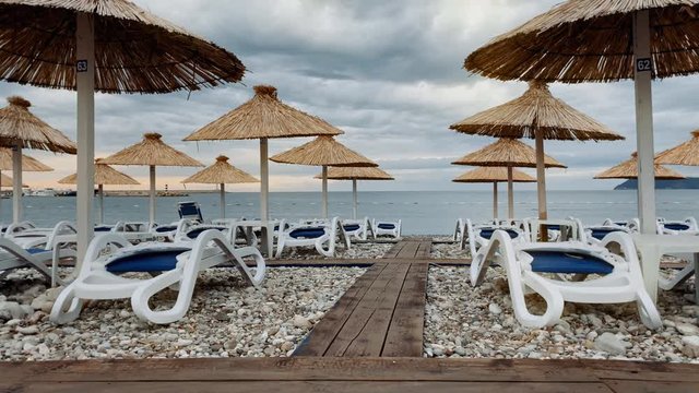 Lonely, empty beach with plastic sunbeds and palm umbrellas at Montenegro, Adriatic Sea, Europe. 
