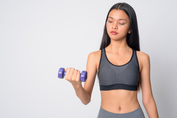 Fototapeta na wymiar Portrait of young beautiful Asian woman exercising with dumbbells and ready for gym