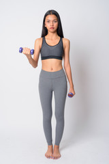 Full body shot of young Asian woman exercising with dumbbells and ready for gym