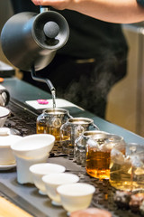 Male hands pouring hot water on glass teapots making tea in strands at a counter in Busan, South Korea.