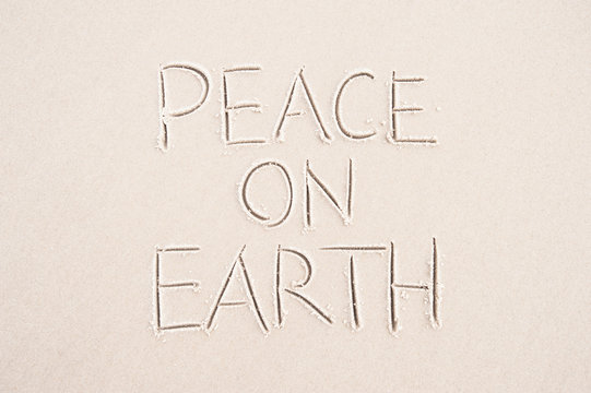 Peace On Earth Holiday Message Handwritten On Smooth Sand Beach