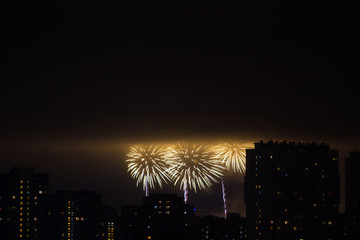 Colorful fireworks over the night city from the height of roofs