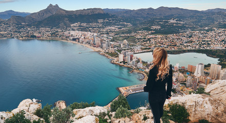 Rear view woman climbed up on peak of Penon de Ifach rock enjoy picturesque view Mediterranean Sea,...