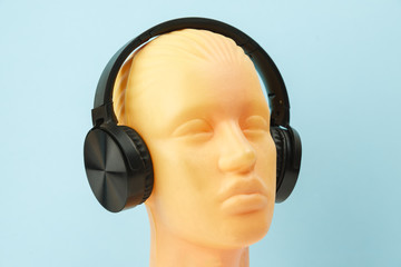 White mannequin head wears wireless headphones on blue background