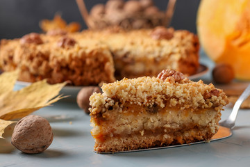 Homemade pumpkin pie with cinnamon and walnuts on a plate, with a piece of cake in the foreground, horizontal orientation