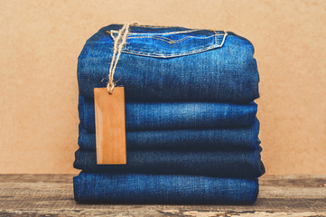 Collection of blue jeans with a label on the wooden table for as a background or advertisement a...