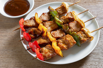 close up of pork barbecue in a ceramic dish served with sauce on wooden table. homemade style food concept.