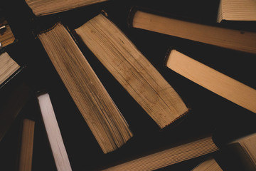 many old and used hardback books or text books seen from above , Old books . Group of old used open hardback books in dust on dark wooden background. Books textbooks for reading and education.