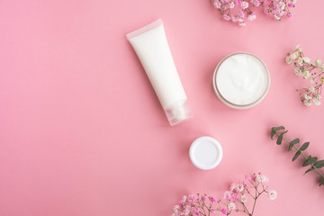 Obraz na płótnie Canvas Cosmetic products, flowers and eucalyptus leaves on a light pink background. Concept natural cosmetics, beauty, skincare. Top view, flat lay, copy space