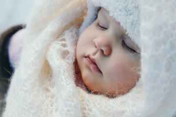 little girl in winter sits in a sled and dressed in a warm down scarf