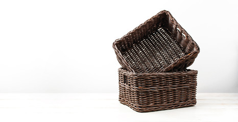 Empty wicker brown rattan basket on a white wooden background and white wall. Natural eco handmade item for home, interior. Home basket