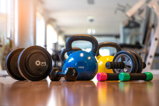 Exercise weights - dumbbell with extra plates , kettlebells, Ab roller wheels on a floor in  center fitness