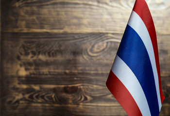 Fototapeta na wymiar Fragment of the flag of the Kingdom of Thailand in the foreground blurred wooden background Kopi space