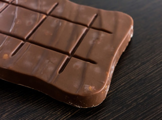 Close up of chocolate bar or piece on wooden background