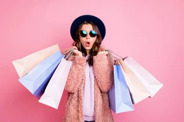 Poster Photo of pretty millennial lady carry many packs shopper tourism abroad look unbelievable sales low prices mall wear fluffy jacket sun specs blue hat isolated pink background © deagreez