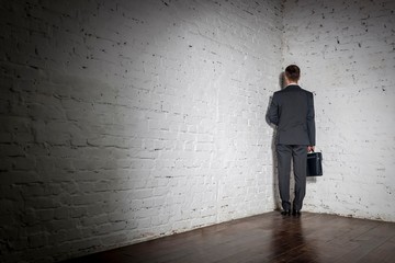 Full length rear view of businessman standing in corner at office